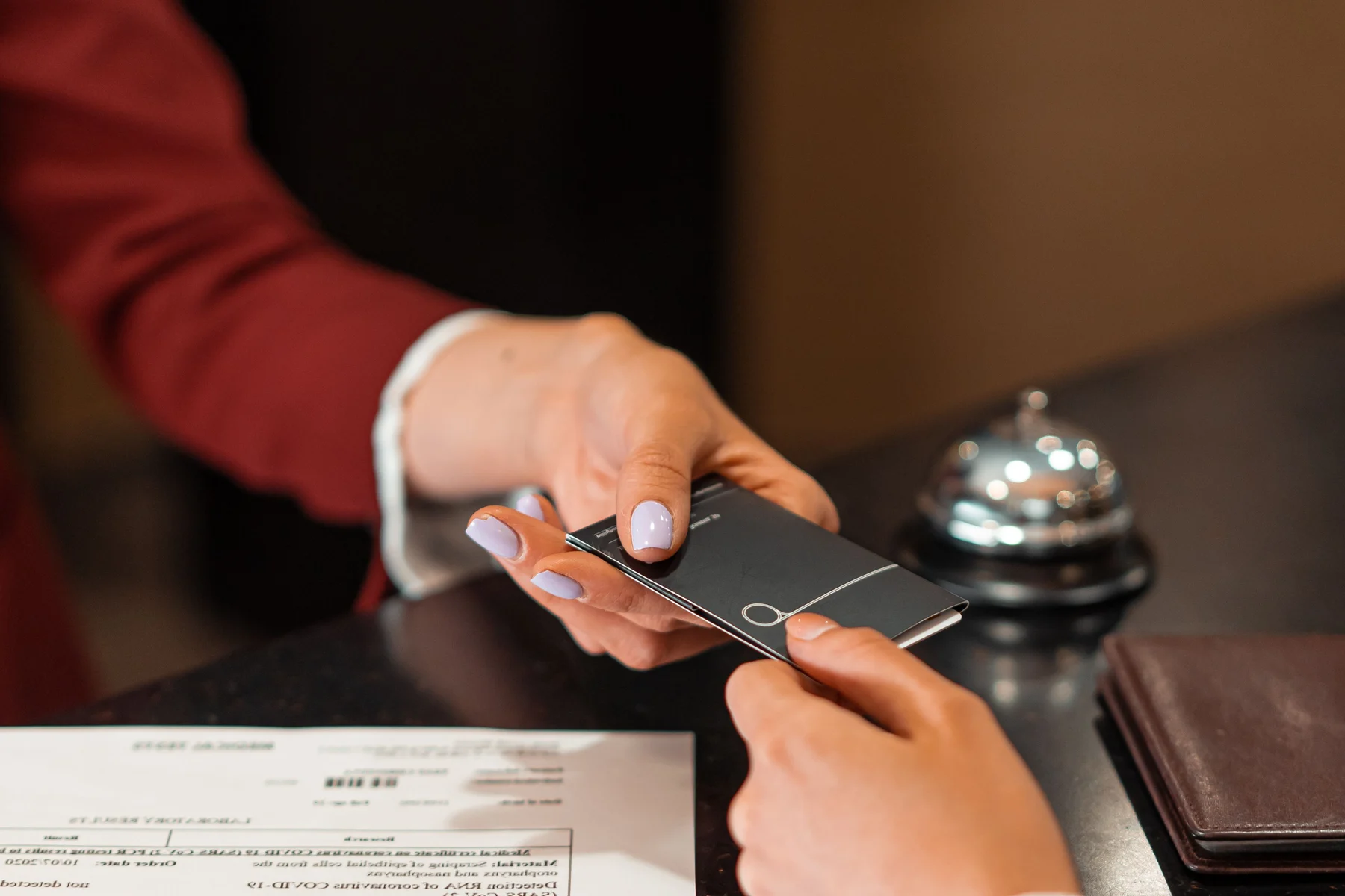 Profissional entrega um cartão-chave a uma pessoa no balcão de um hotel