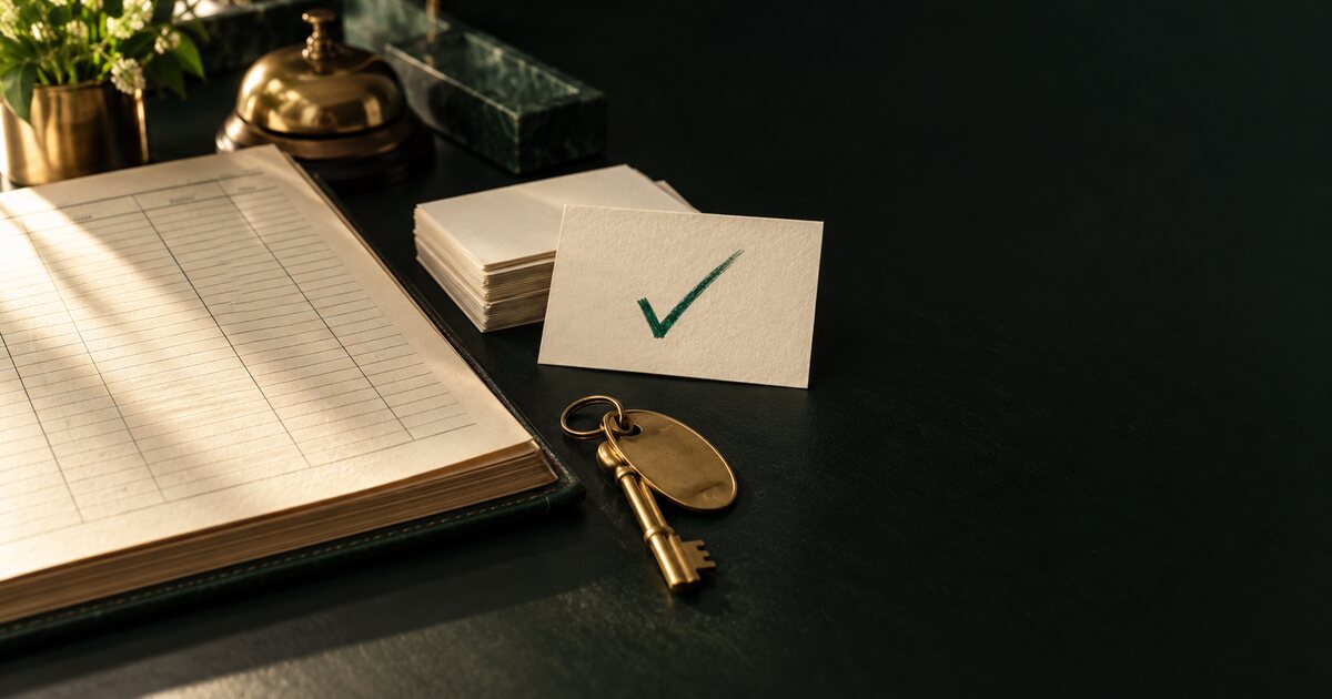 Livro de operação hoteleira, cartões de papel e chave de quarto sobre uma mesa escura; um cartão está marcado com um sinal verde.
