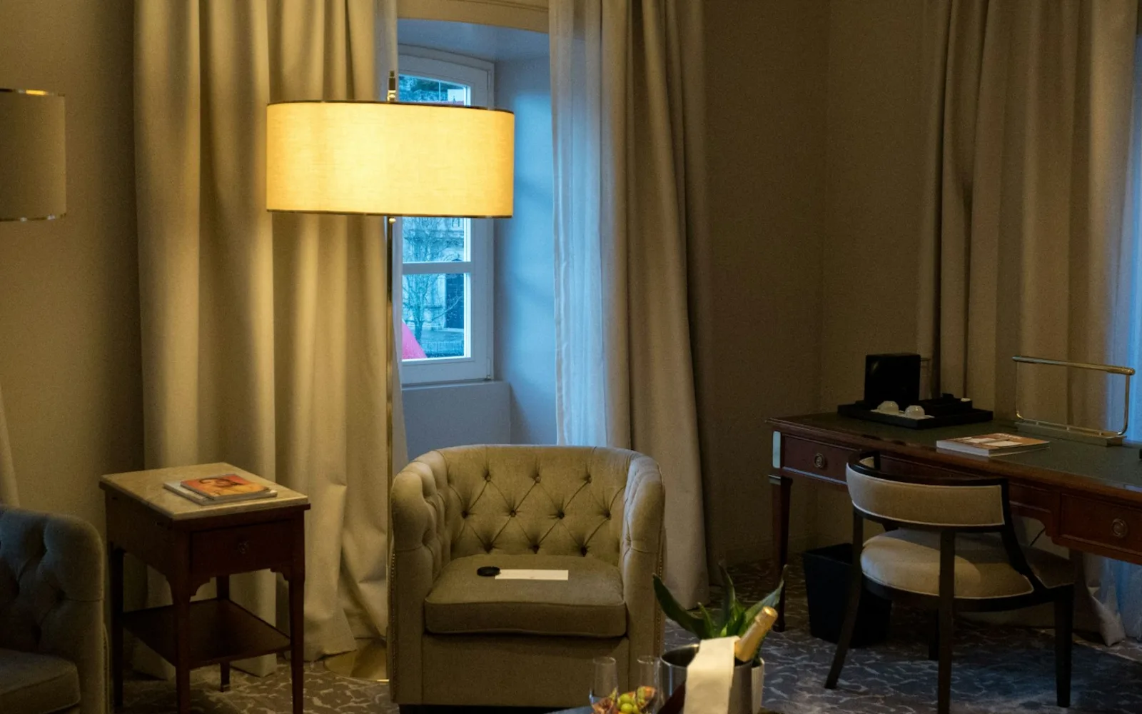 Quarto de hotel com área de estar, mesa de trabalho e serviço de boas-vindas